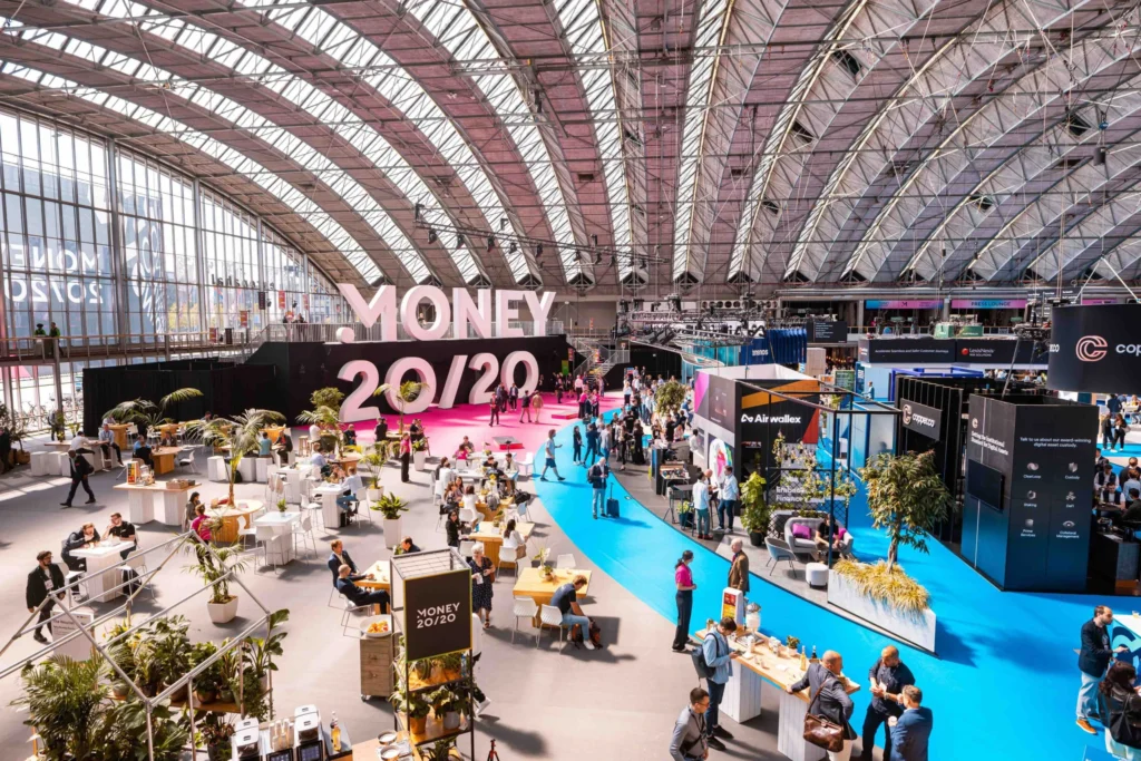 Large exhibition hall at Money 20/20 event with fintech booths, attendees networking, and branded displays.